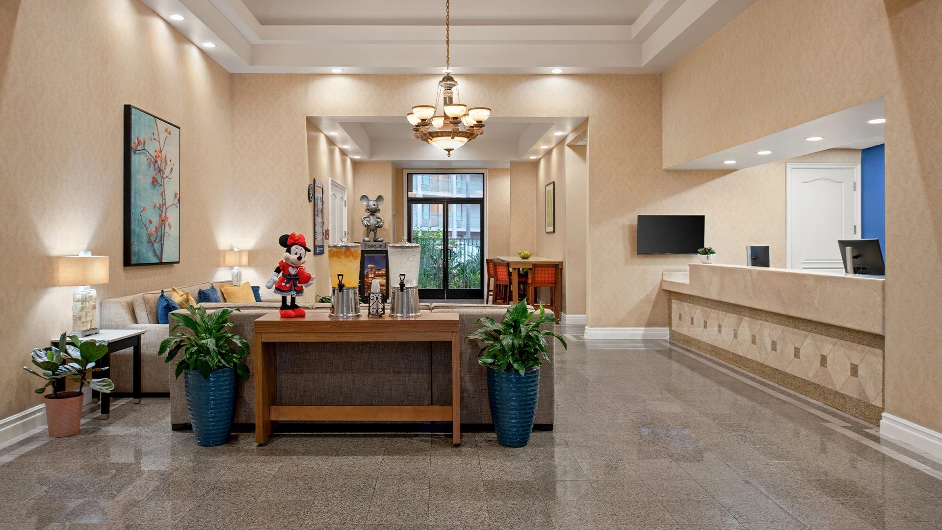 A hotel lobby with a reception desk, sofa, and chandelier.
