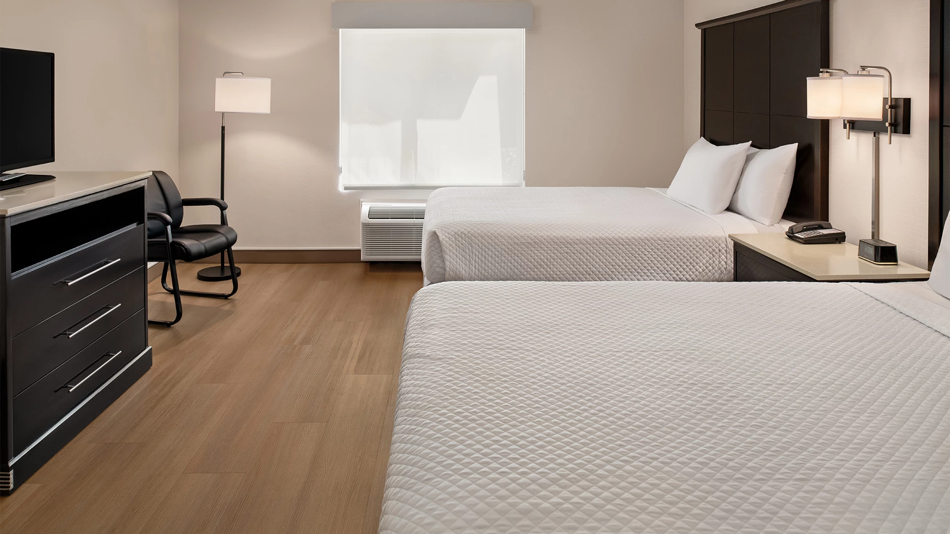 A hotel room with two beds, a TV, and a window