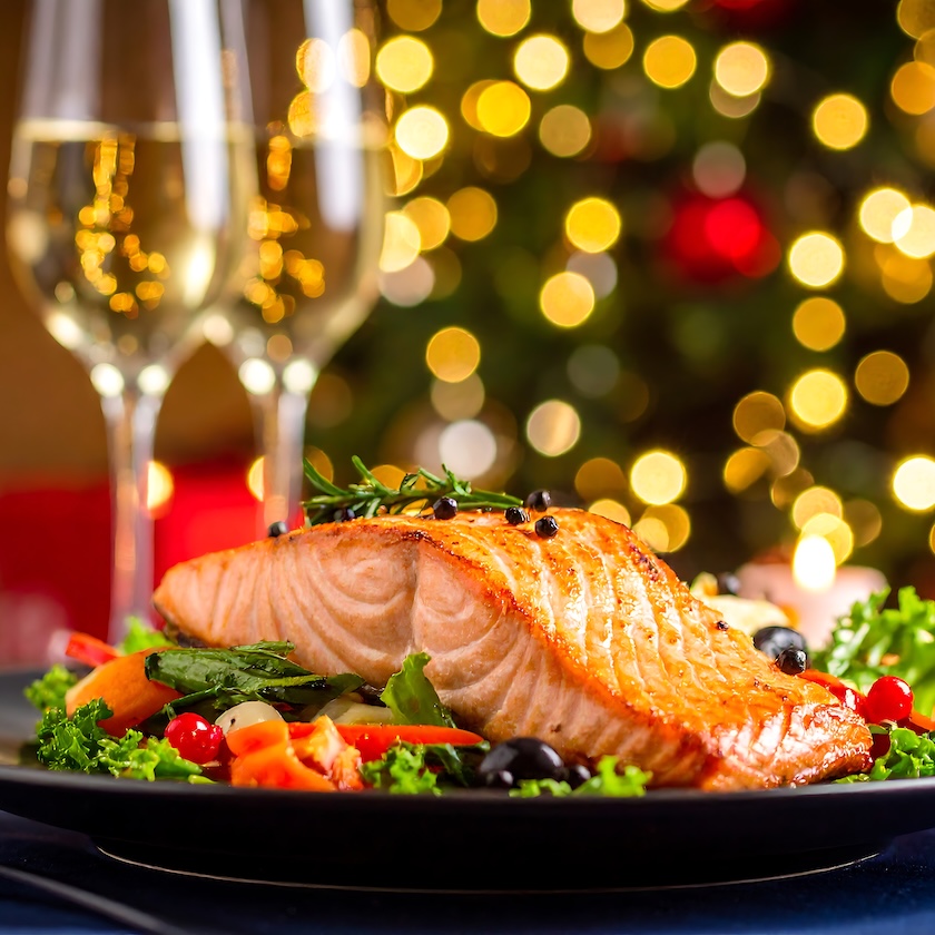 a plate of food with wine glasses and lights in the background