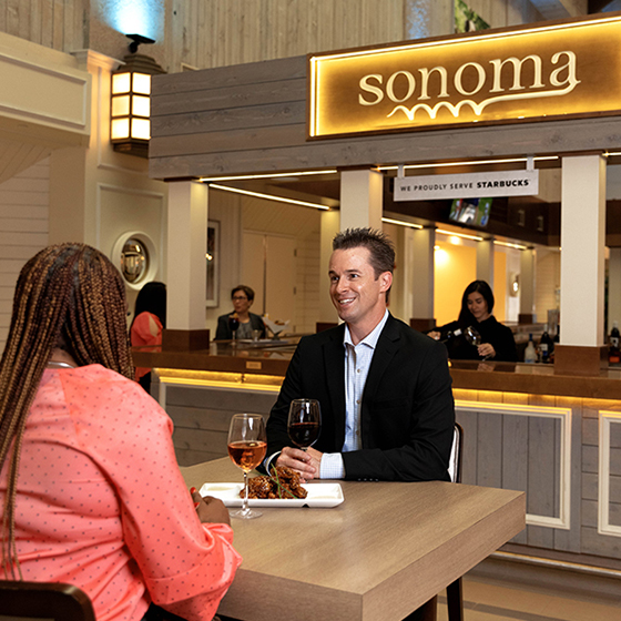 a man and woman sitting at a table with wine
