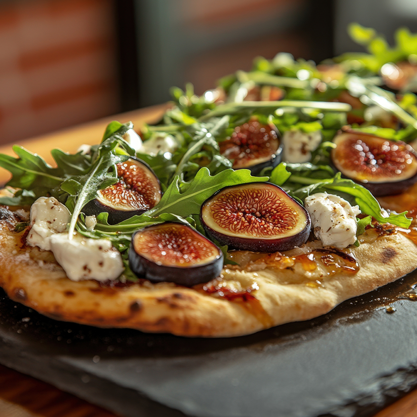 a pizza with figs and cheese on a black plate