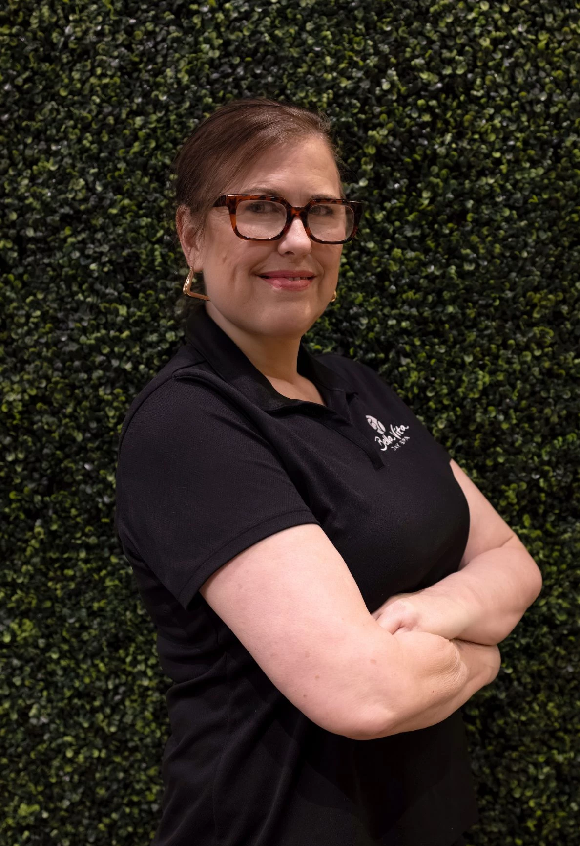 a woman in glasses smiling with arms crossed