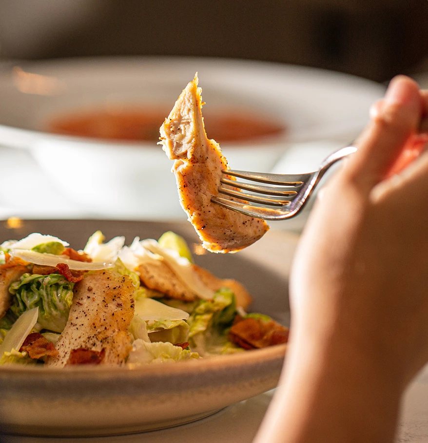 a person holding a fork over a salad