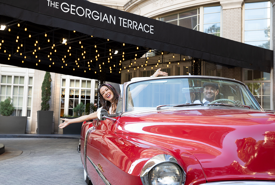 a woman in a red convertible car with a man in the background