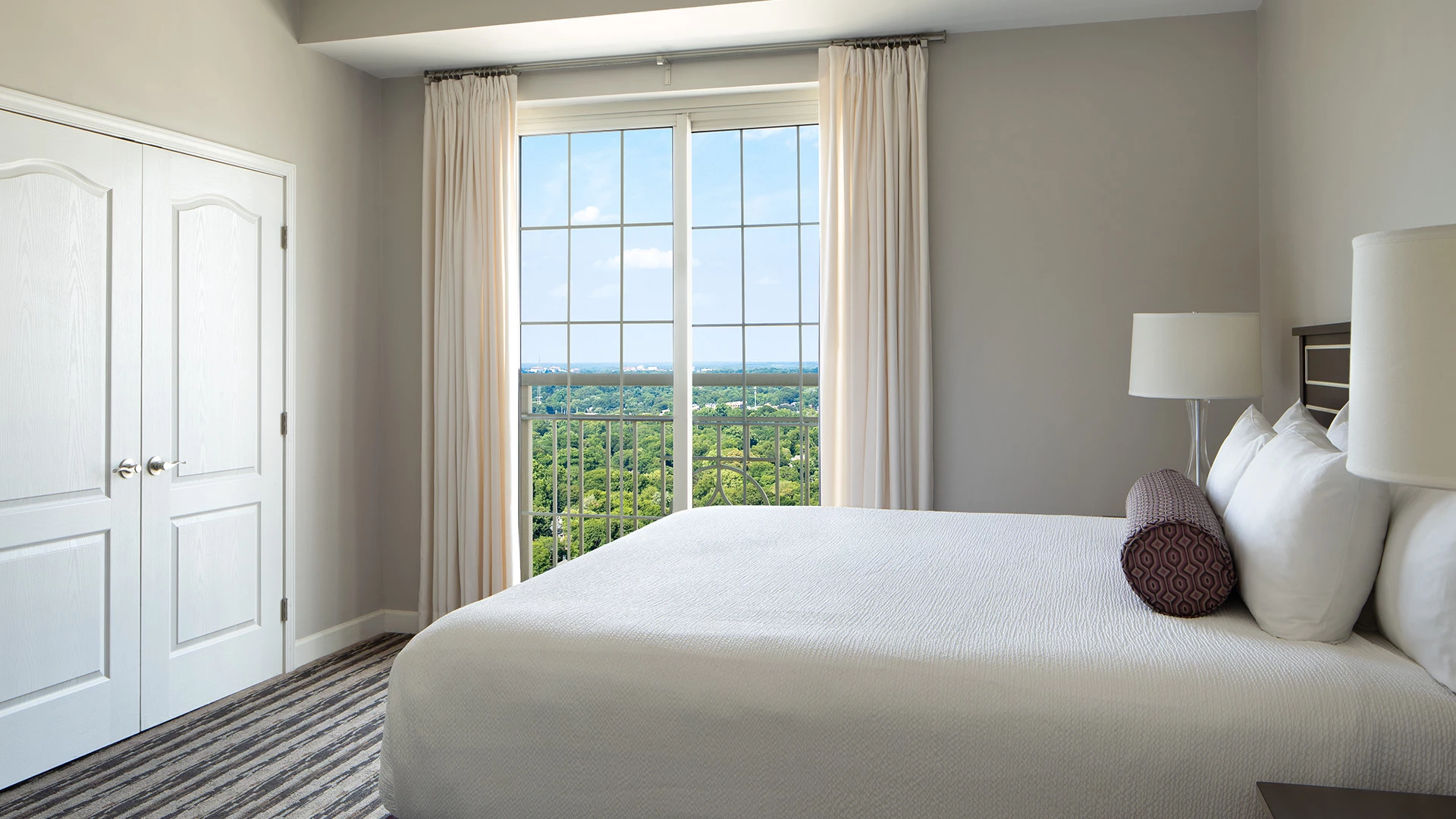 A hotel room with a large bed, window, and door.