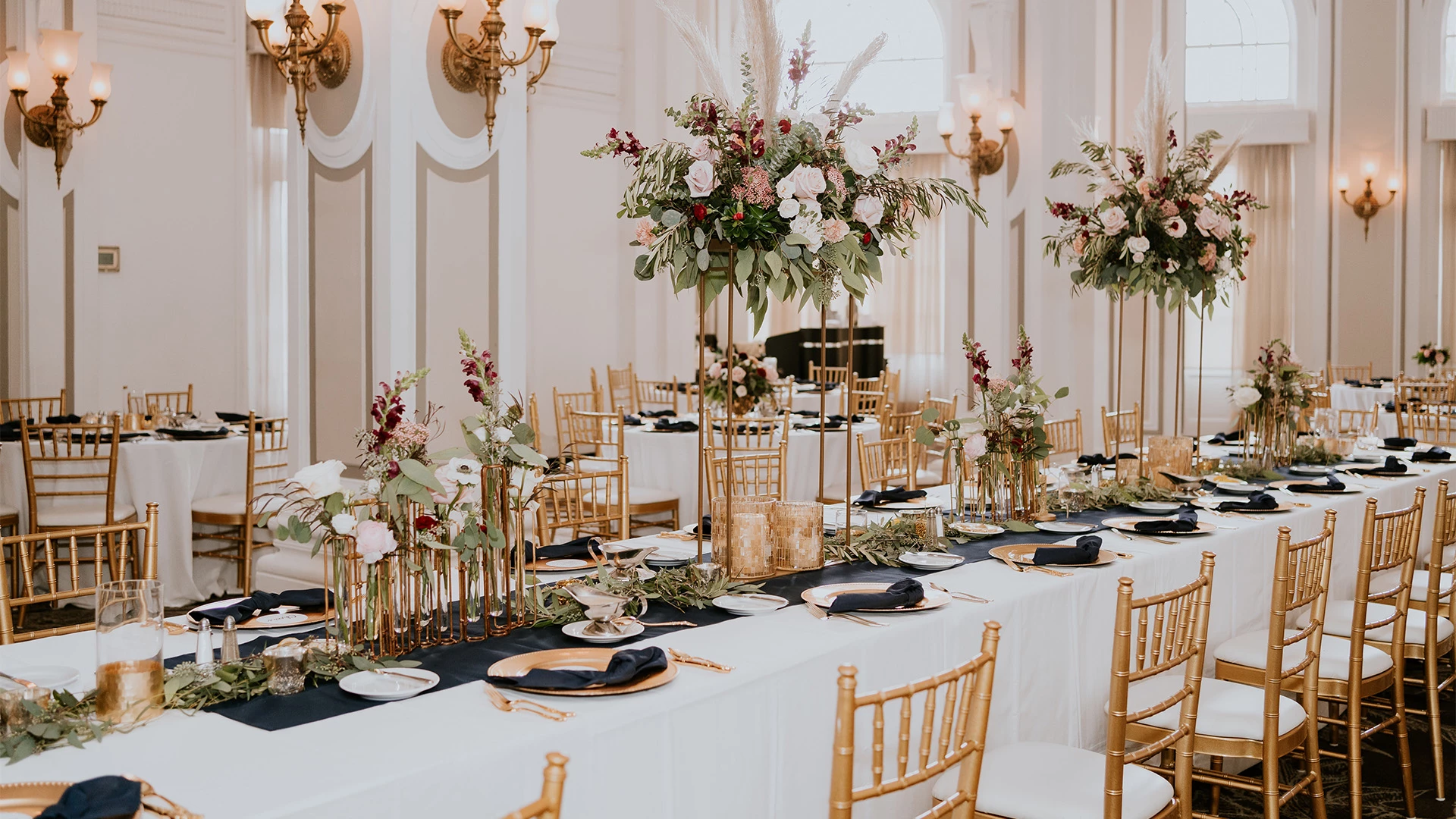 a formal dining room with white tablecloths, gold chairs, and flower arrangements