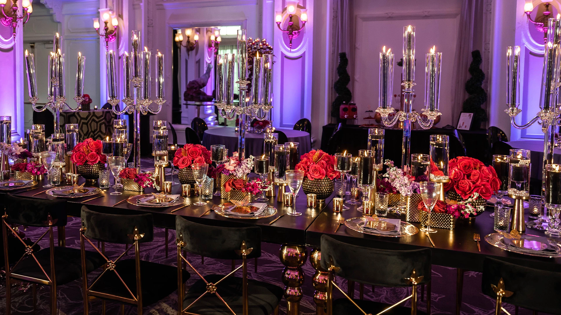 A long table set for a formal dinner with candles, flowers, and wine glasses.