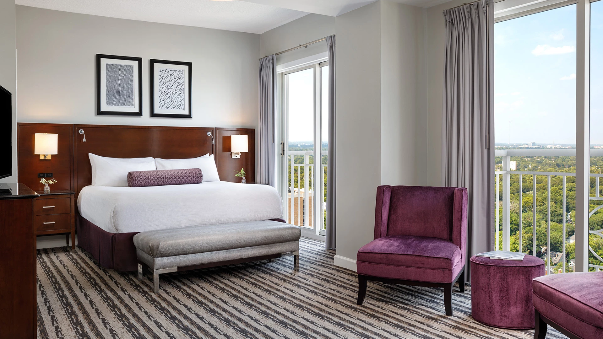 A hotel room with a large bed, balcony, and city view