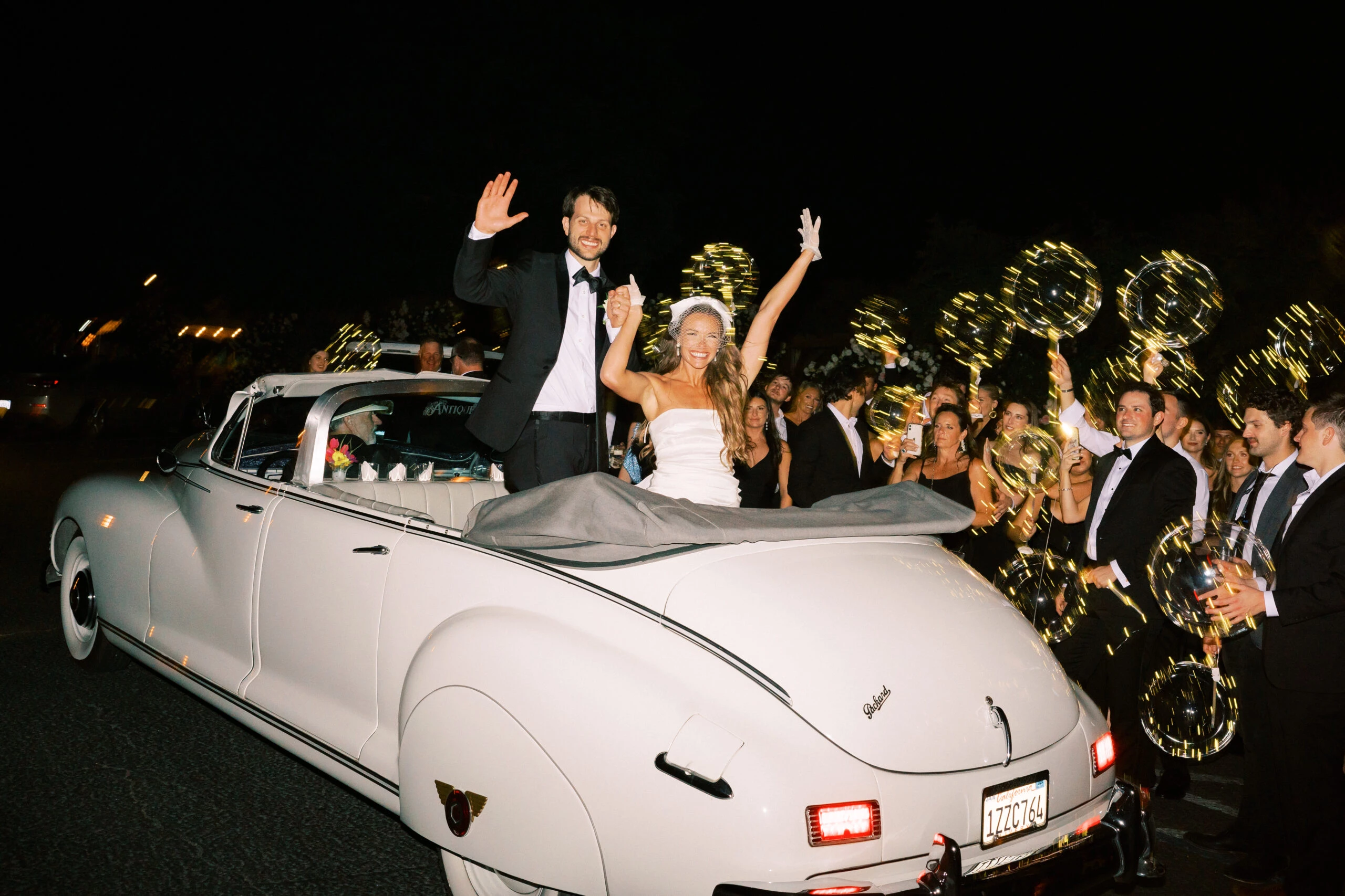 a man and woman in a wedding dress and a car with people in the back