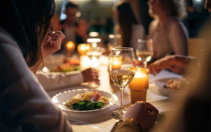 a group of people sitting at a table with food and wine glasses