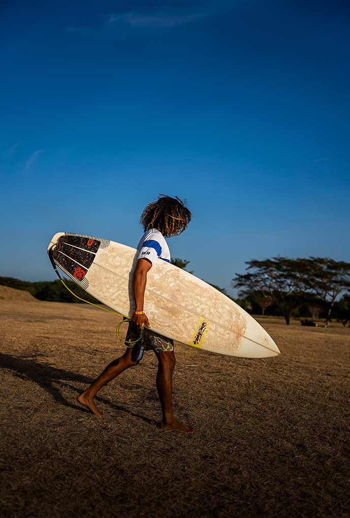 a man walking with a surfboard