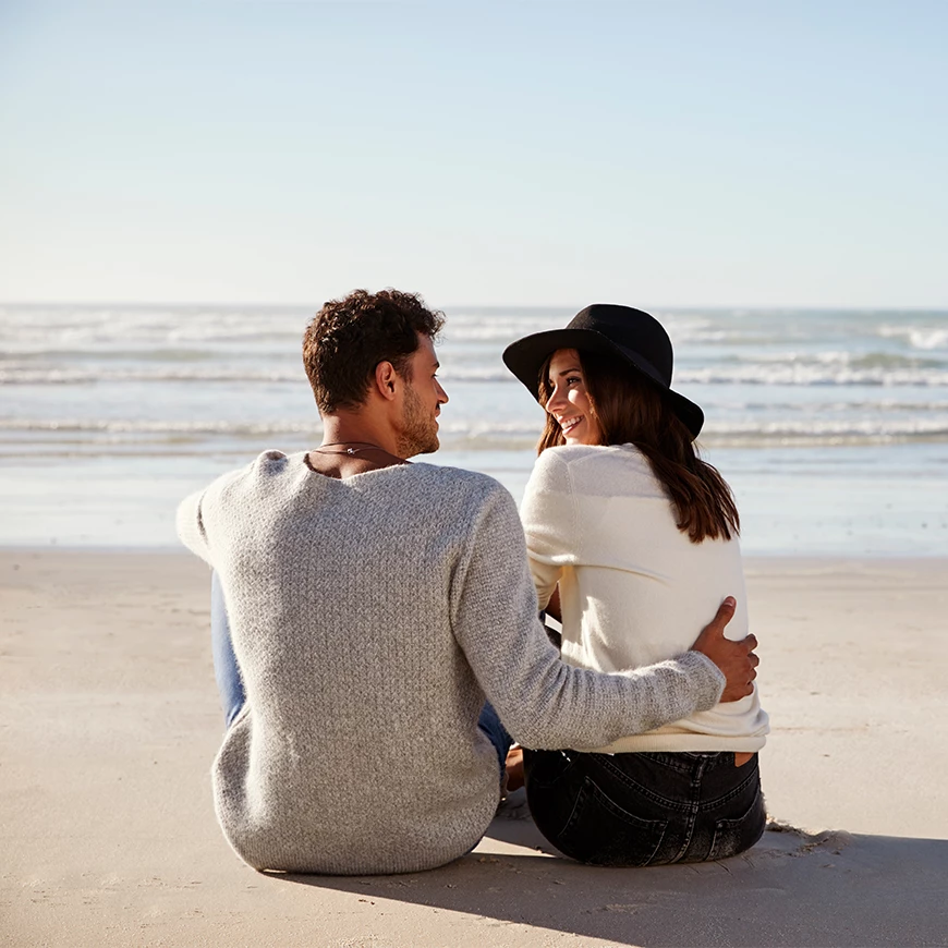 a man and woman sitting on a beach