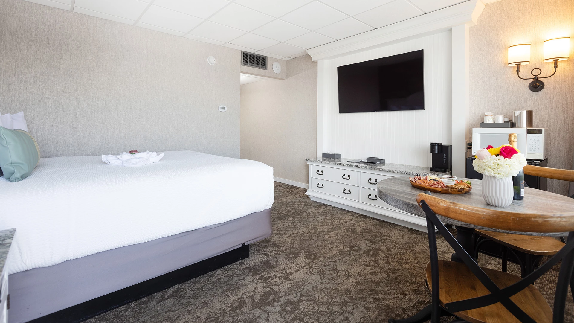 A hotel room with a bed, TV, table, and chair.