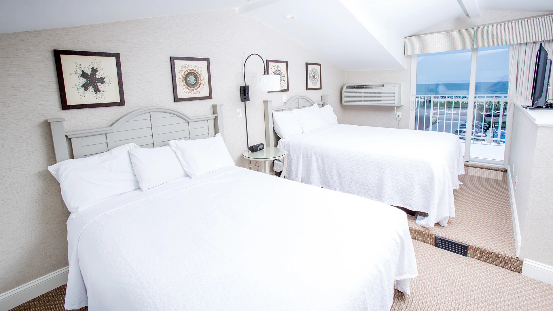 A hotel room with two beds, a window with a view, and beige walls.