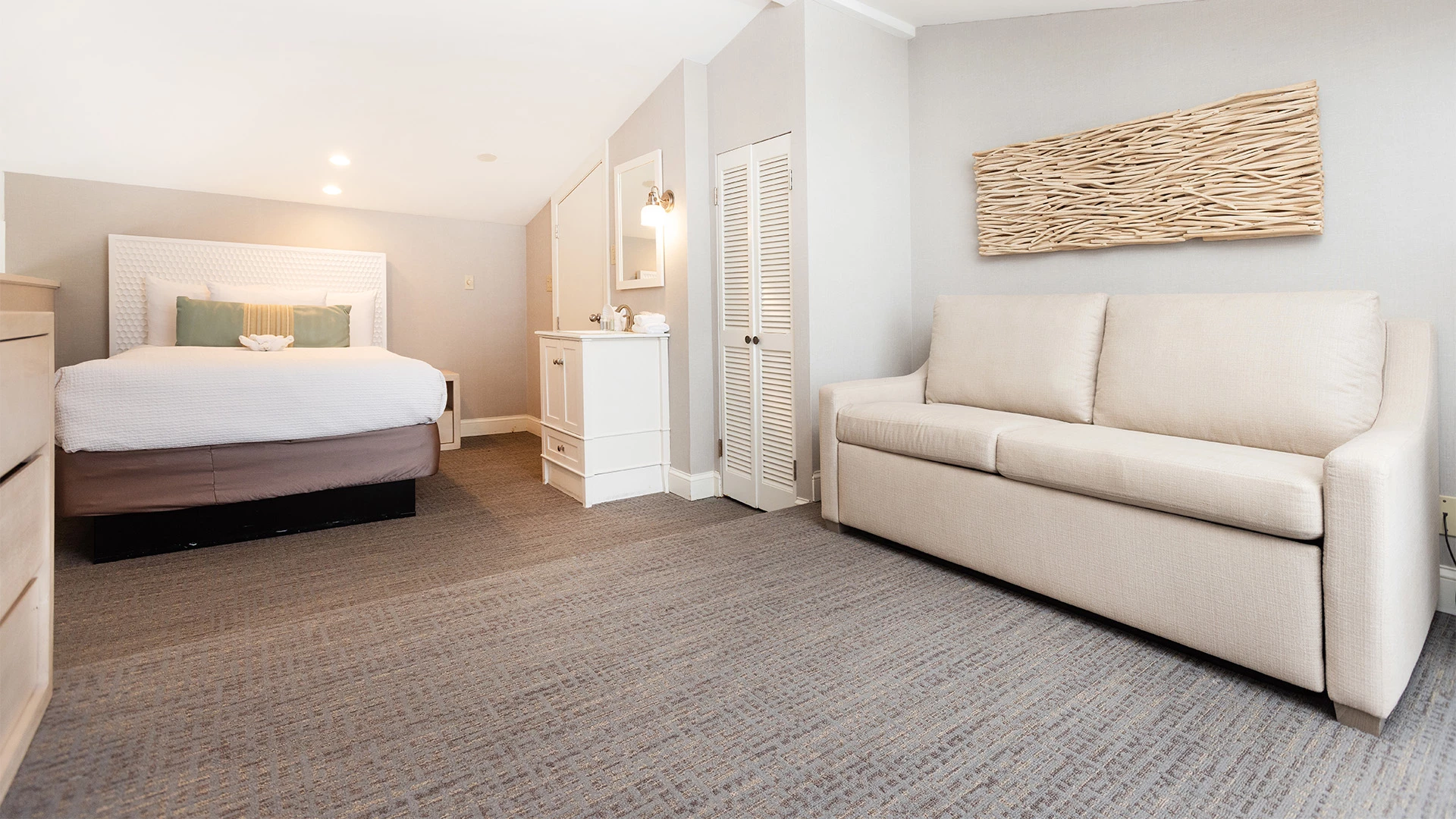 A wide view of a hotel room with a bed, sofa, and artwork.