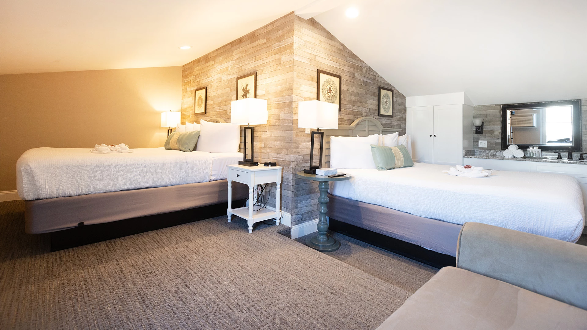 A hotel room with two beds, a wooden accent wall, and lamps.