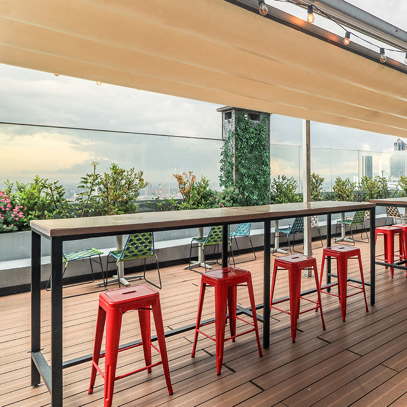 a patio with red stools and tables