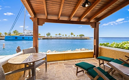a patio with a table and chairs and a boat in the water