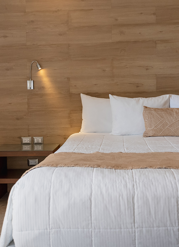 a bed with pillows and a lamp on the wall