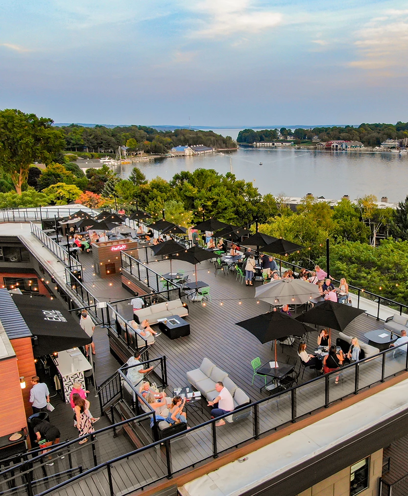 a rooftop patio with people sitting at tables and umbrellas