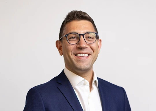 a man in a suit and glasses smiling