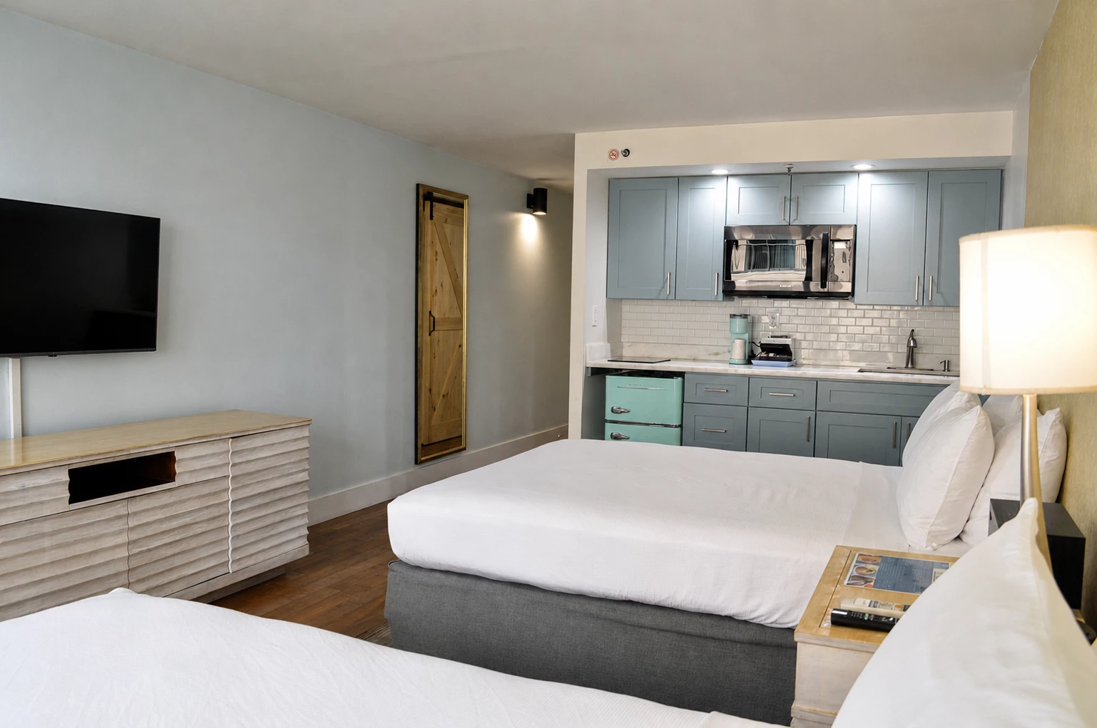 A hotel room with a kitchenette, two beds, and a TV