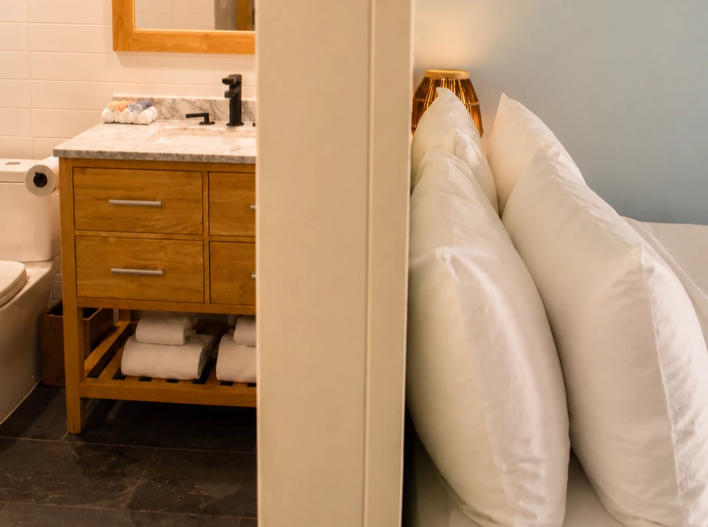 A bathroom with a marble countertop, wooden cabinet, and tiled wall