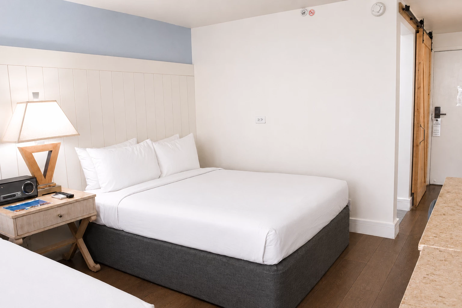 A hotel room with a bed, nightstand, and lamp