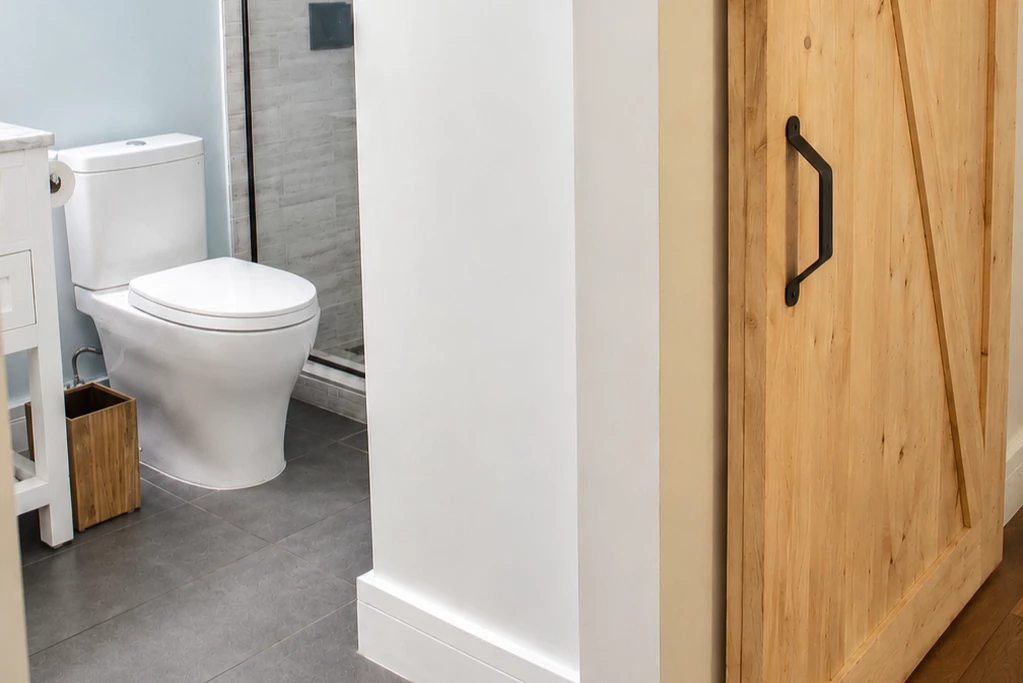 A bathroom with a toilet, shower, and wooden door