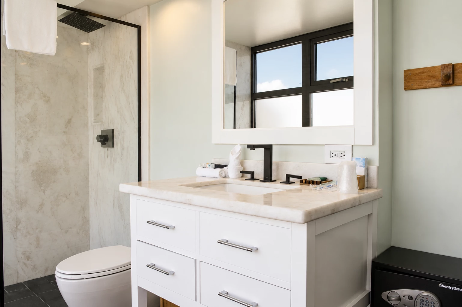 a clean bathroom with a white vanity, marble countertop, and black shower