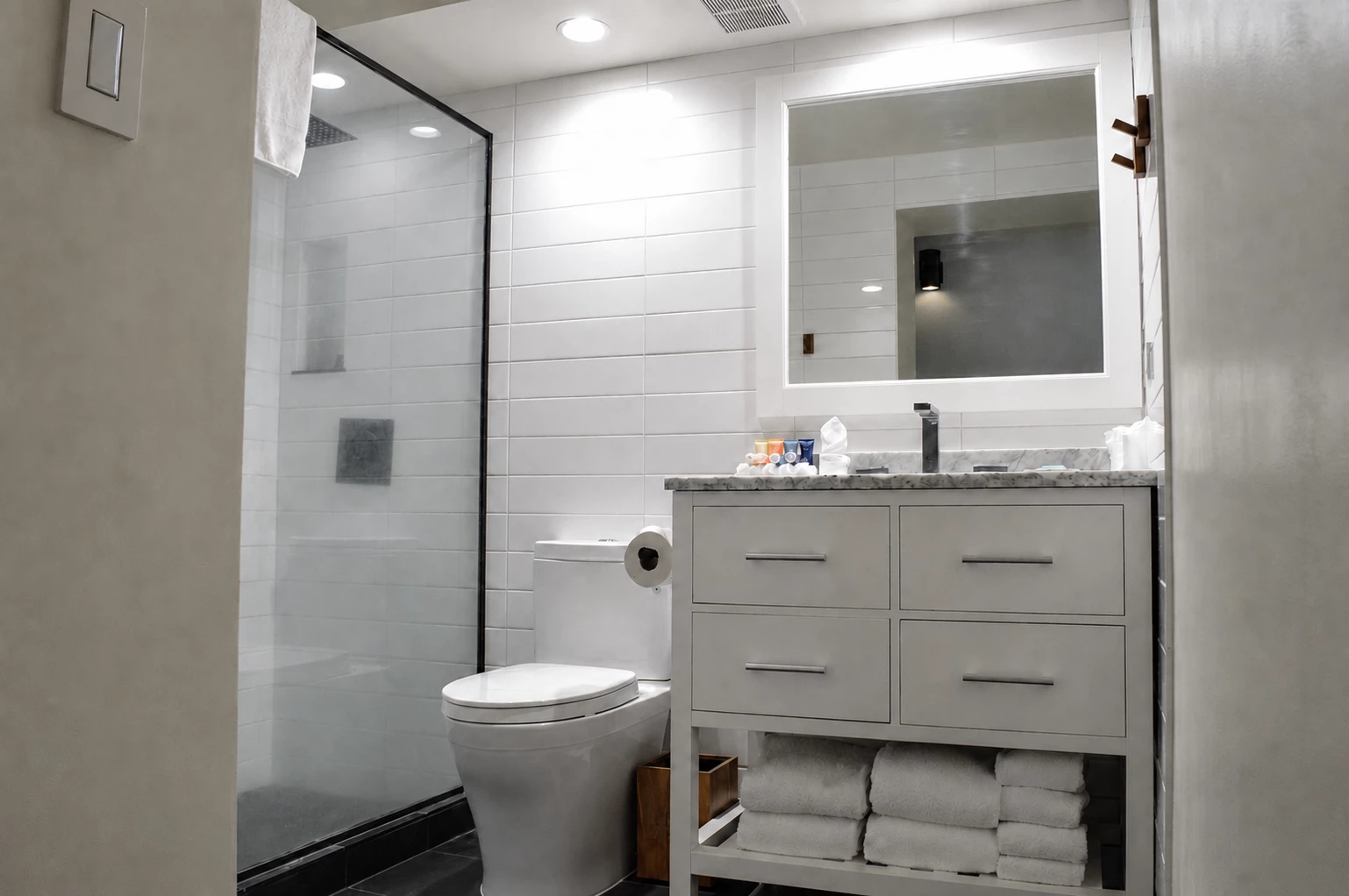 A clean bathroom with a shower, toilet, vanity, and towels
