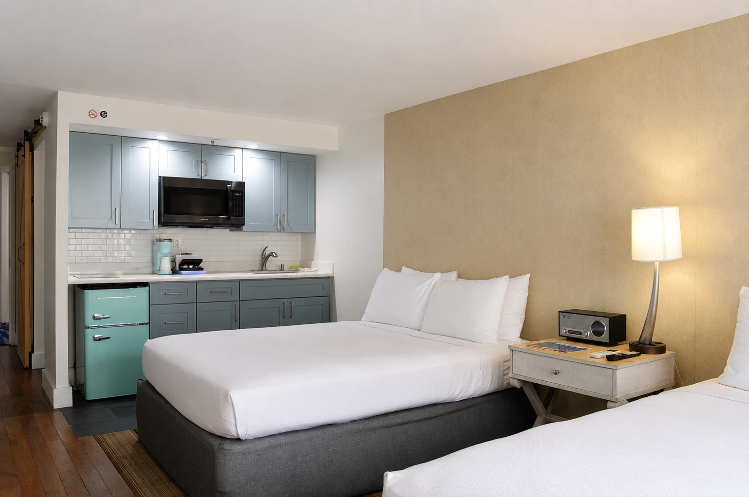 A hotel room with a kitchenette, two beds, and modern amenities.