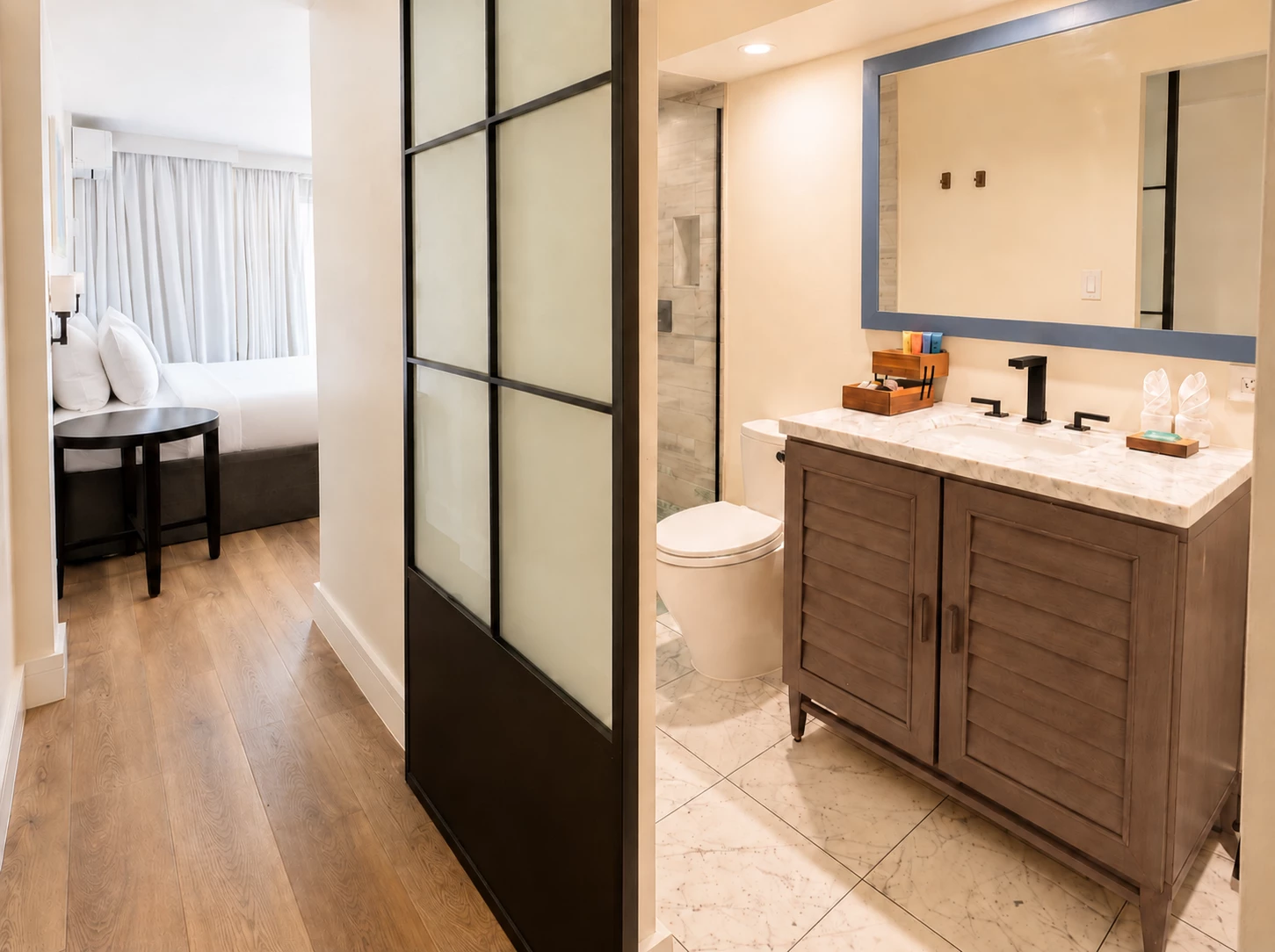 A modern bathroom with a large mirror, marble countertop, and glass shower door.