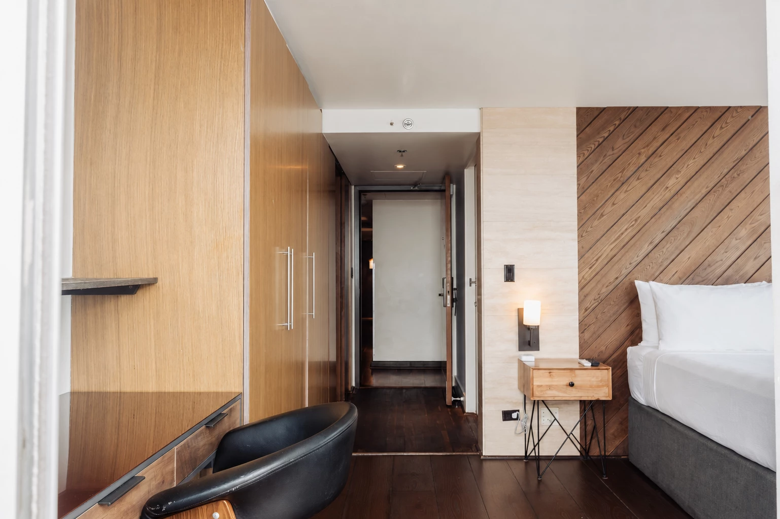A hotel room with a bed, chair, and wooden paneling