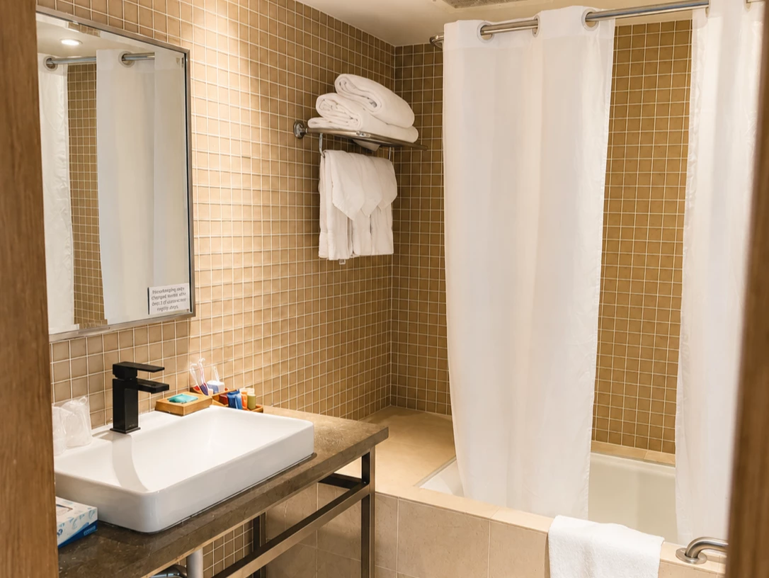 A bathroom with a sink, mirror, shower, and tiled walls