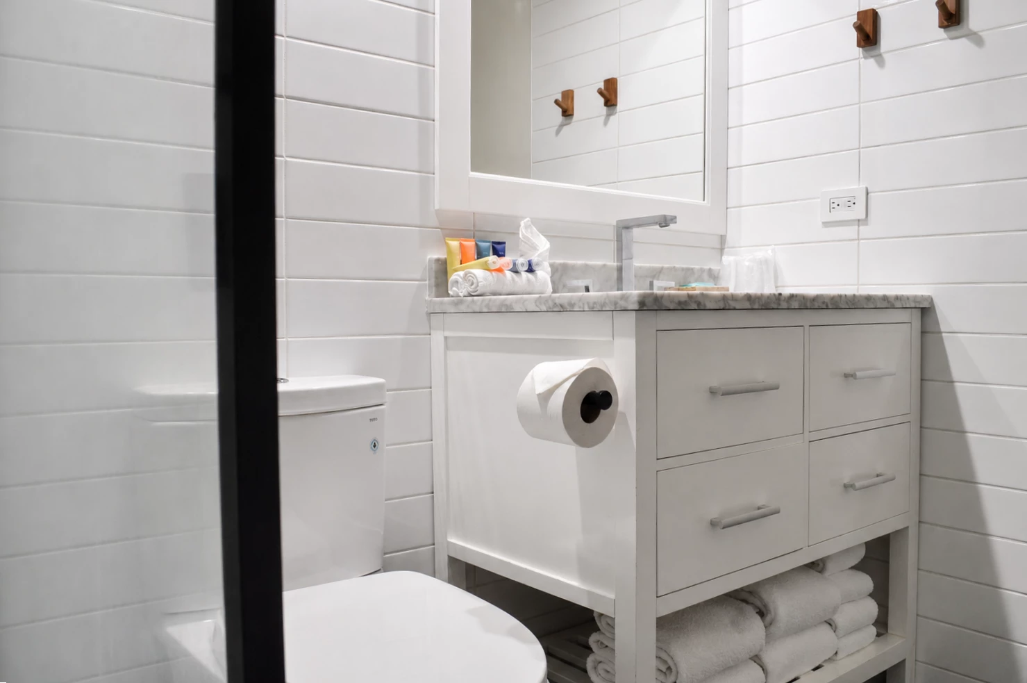 A clean bathroom with white tile, a marble countertop, and a toilet