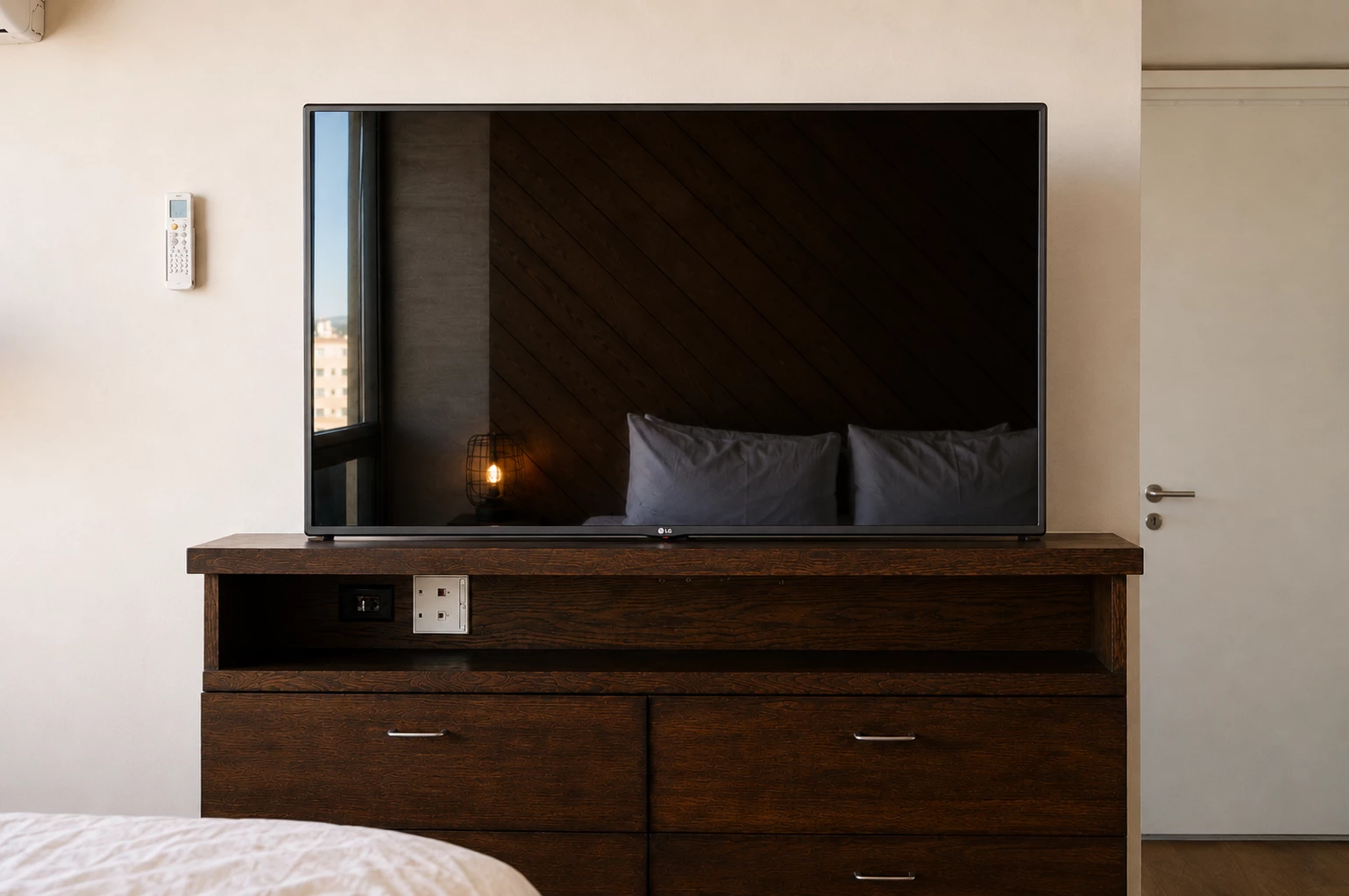 A bedroom with a large TV on top of a dresser