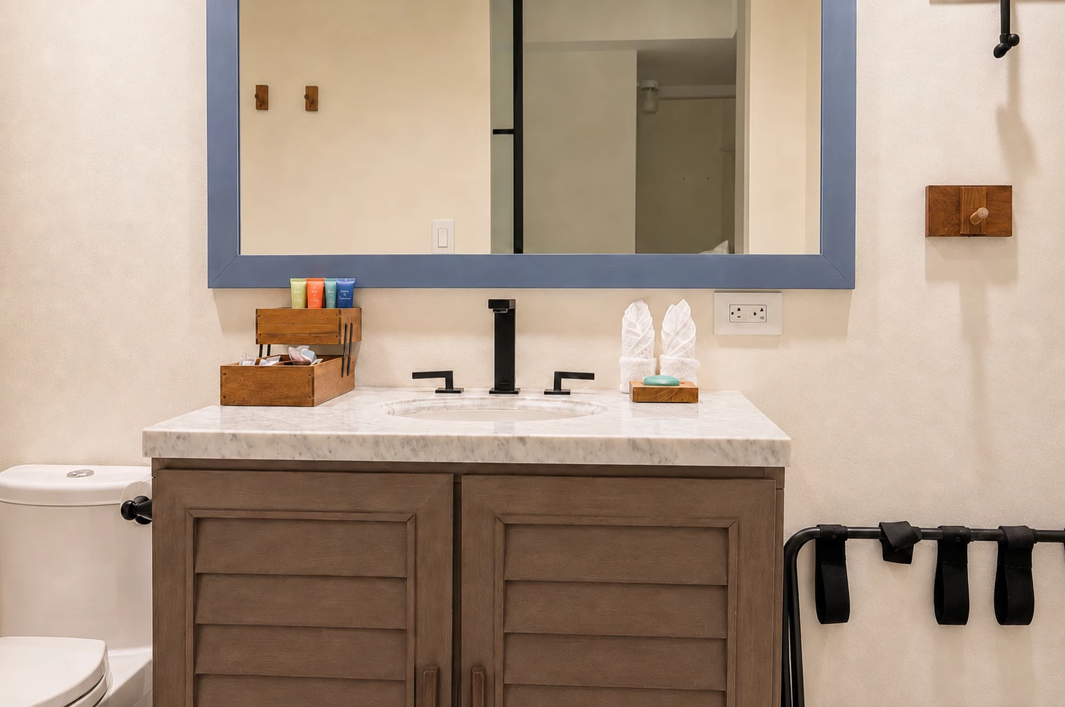 A bathroom sink with a marble countertop, wooden cabinets, and black fixtures.