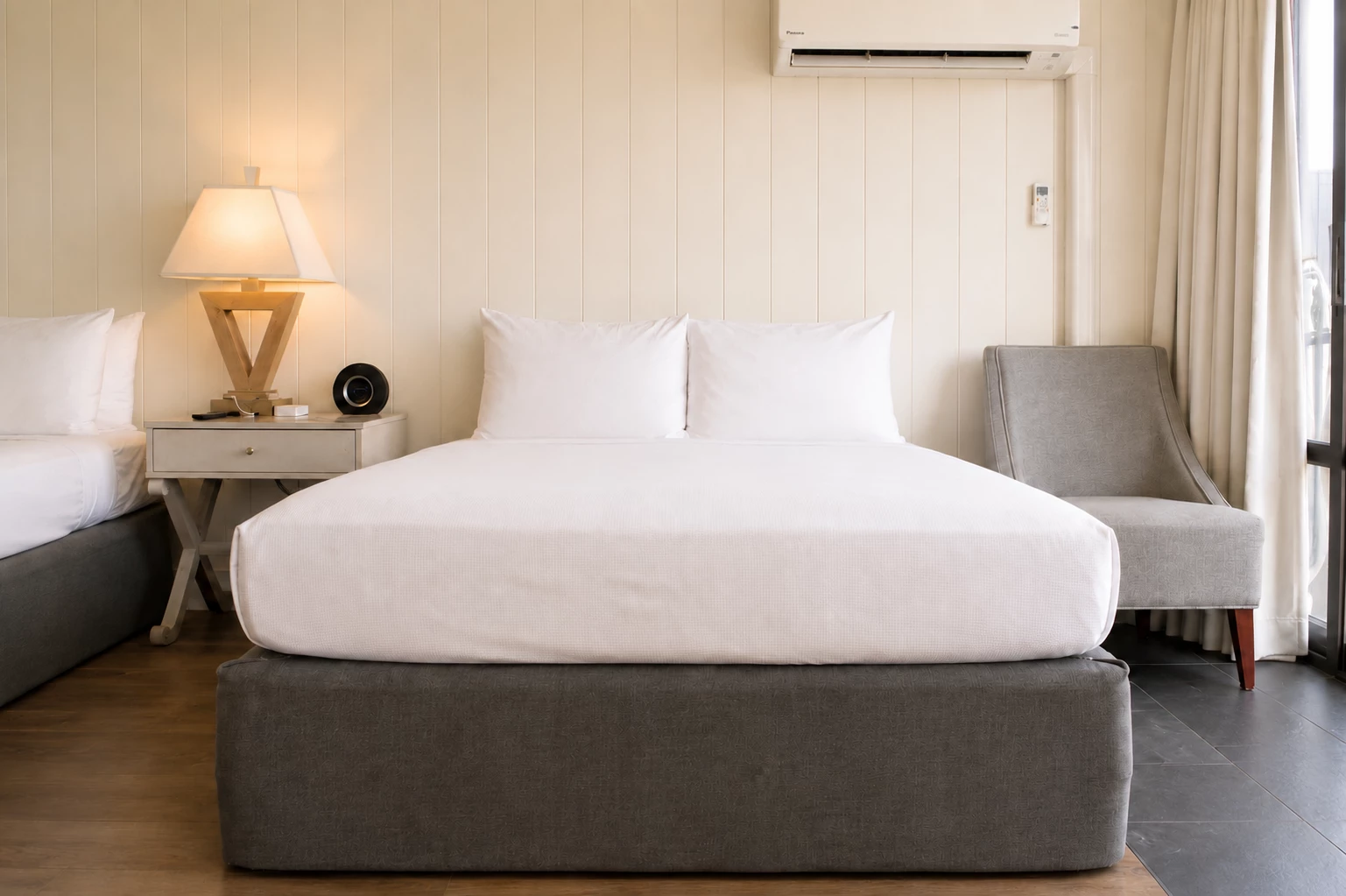 A hotel room with a large bed, chair, and nightstand.