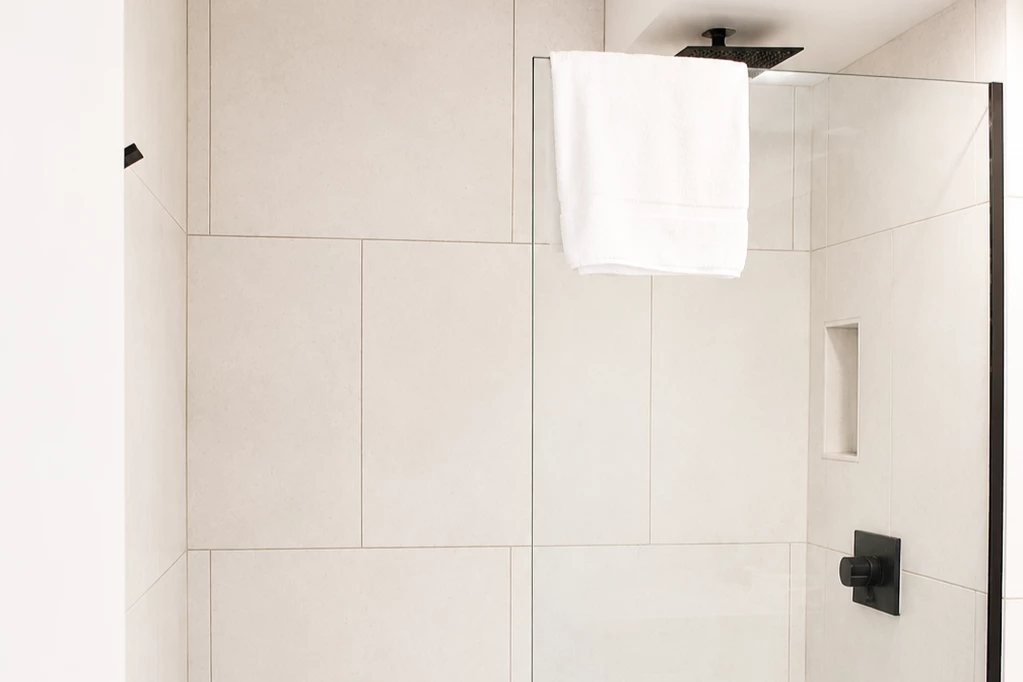 A modern shower with white tiles and black fixtures