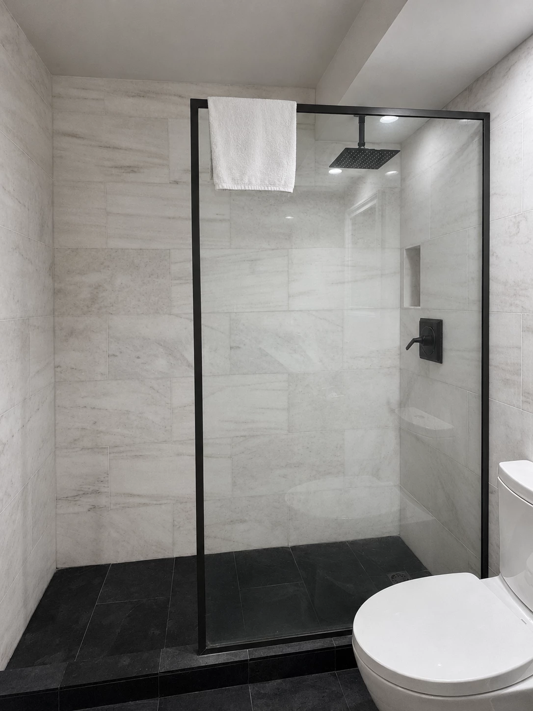 A modern bathroom with a glass-enclosed shower, white marble walls, and a black floor.