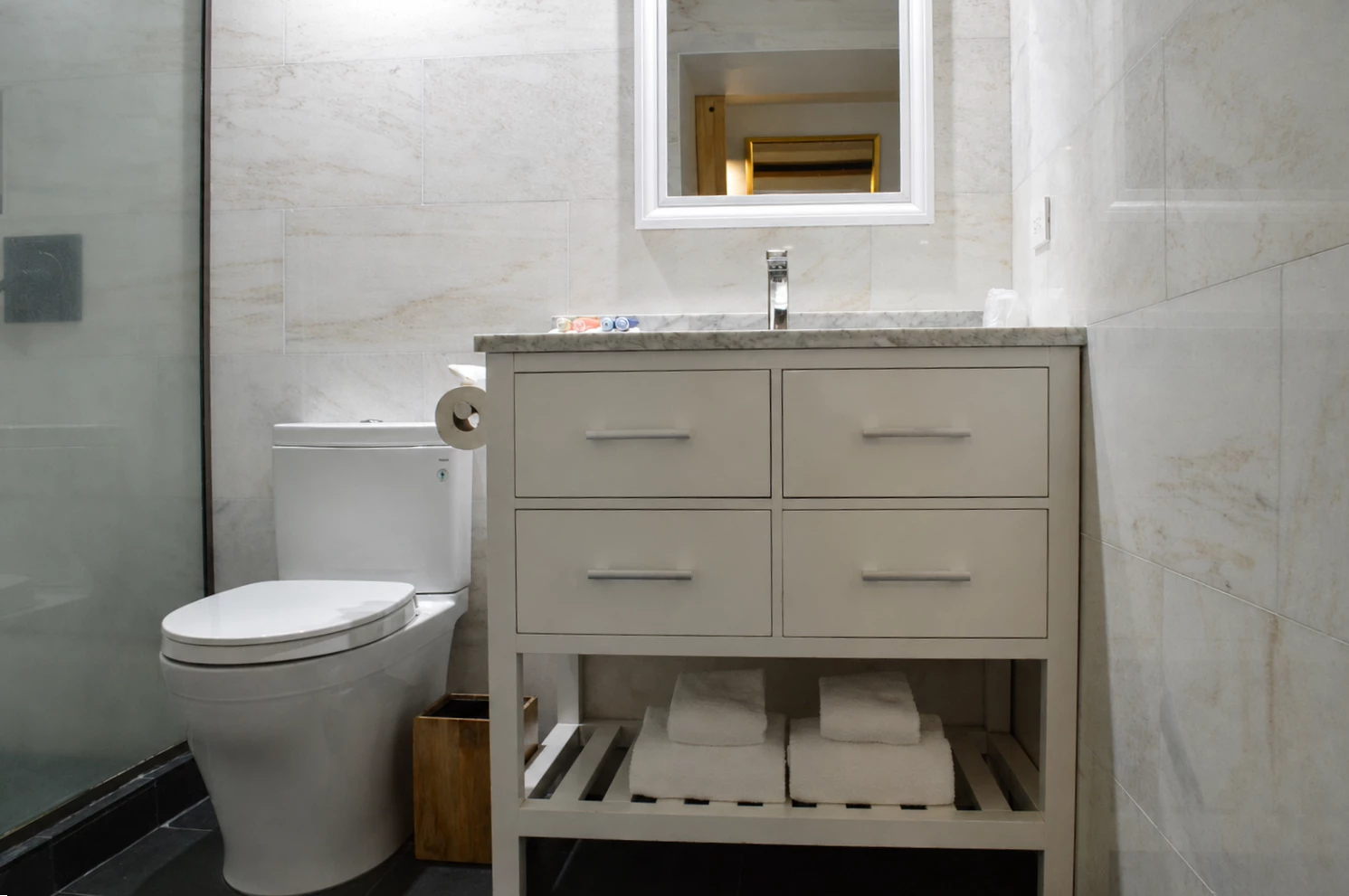 A clean and modern bathroom with a white vanity, marble countertop, and a shower with a glass door.