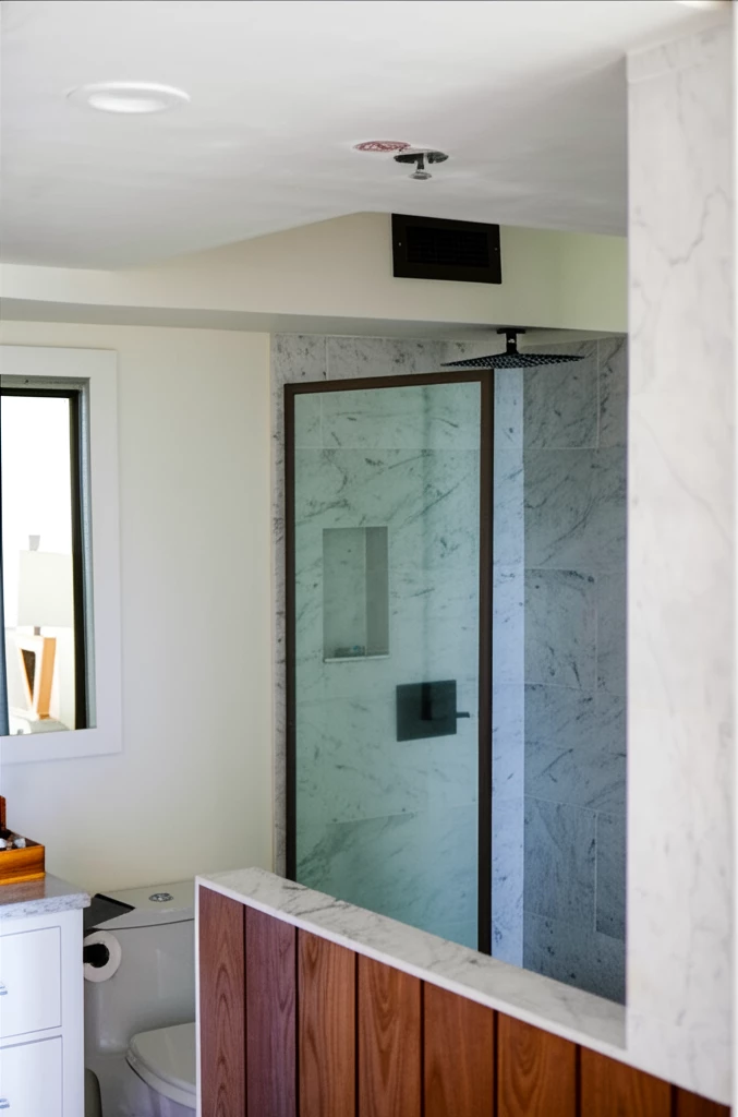 A modern bathroom with a marble-tiled shower, glass door, and rain showerhead.