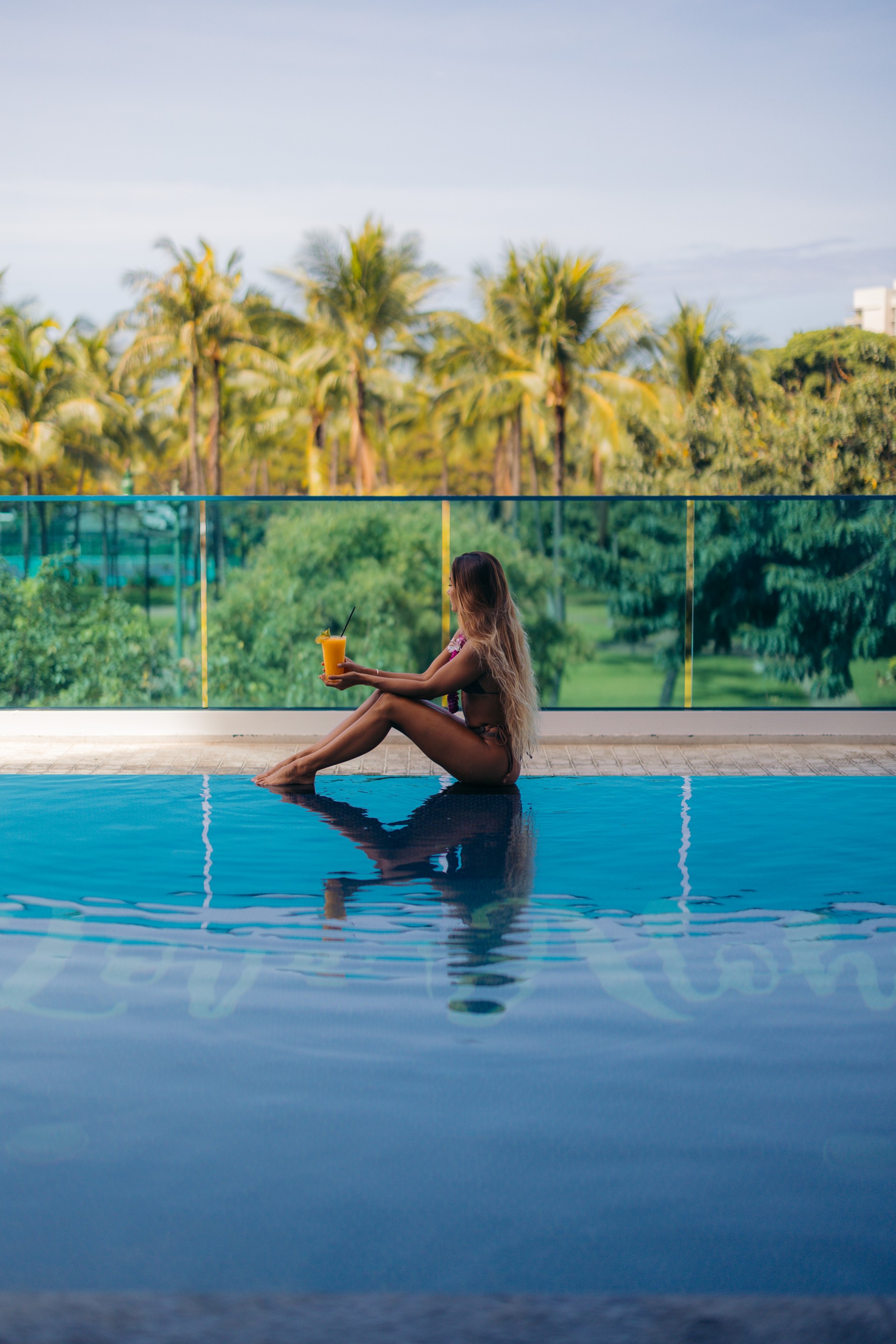 a woman sitting on a pool with a drink in her hand