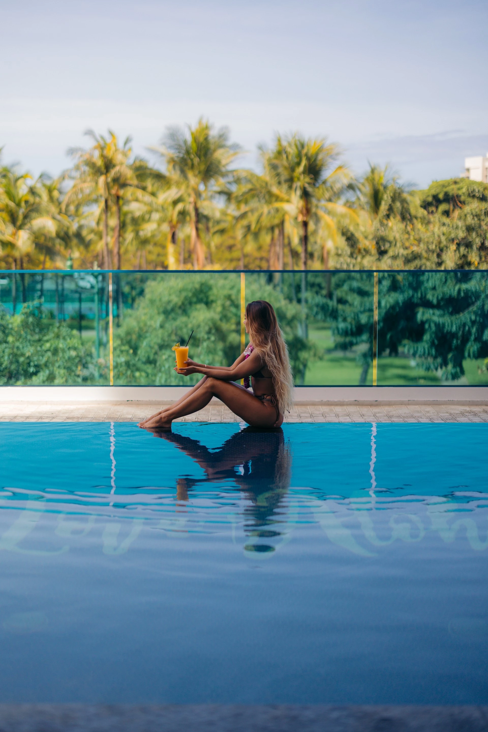 a woman sitting on a pool with a drink in her hand