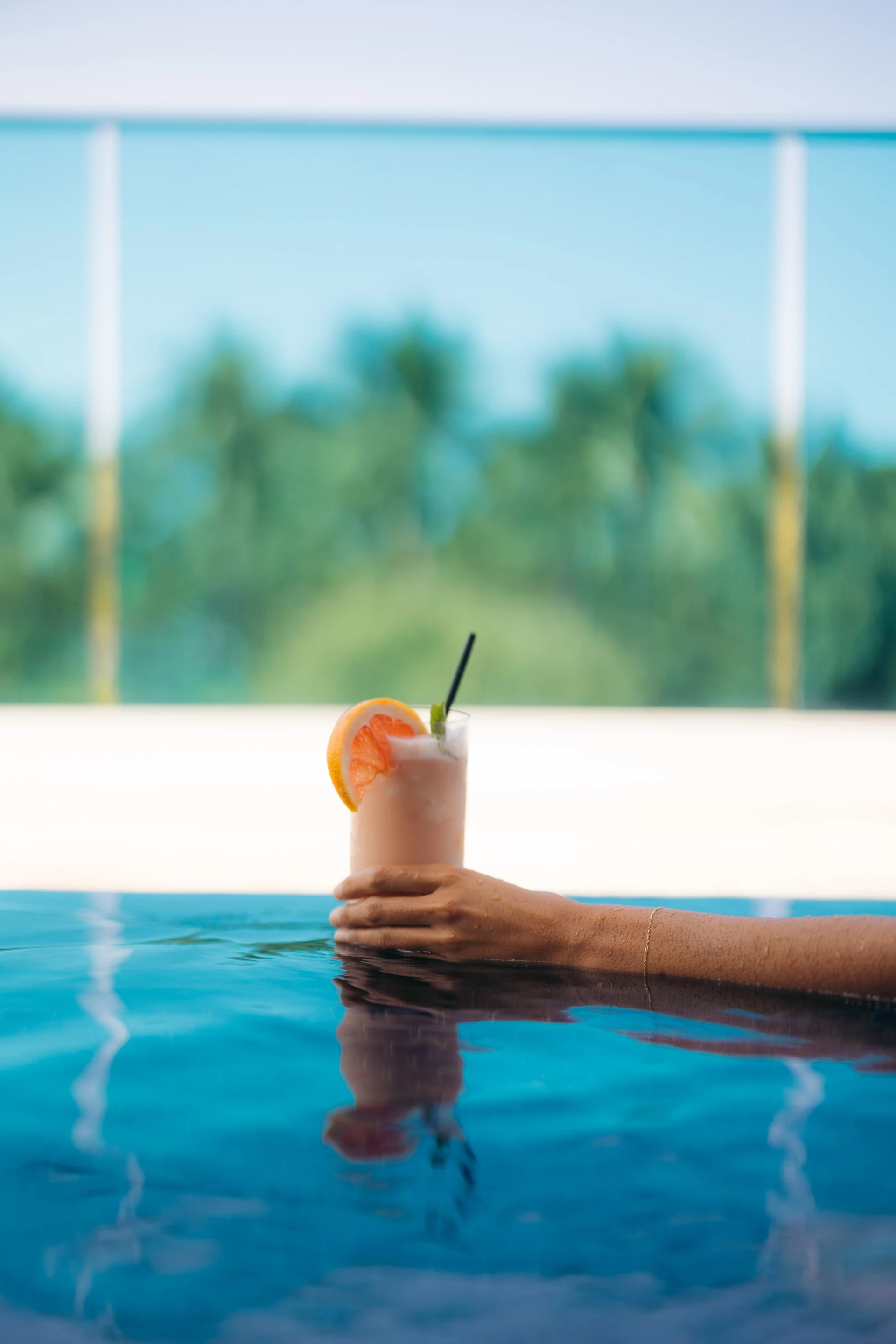 a hand holding a drink in a pool