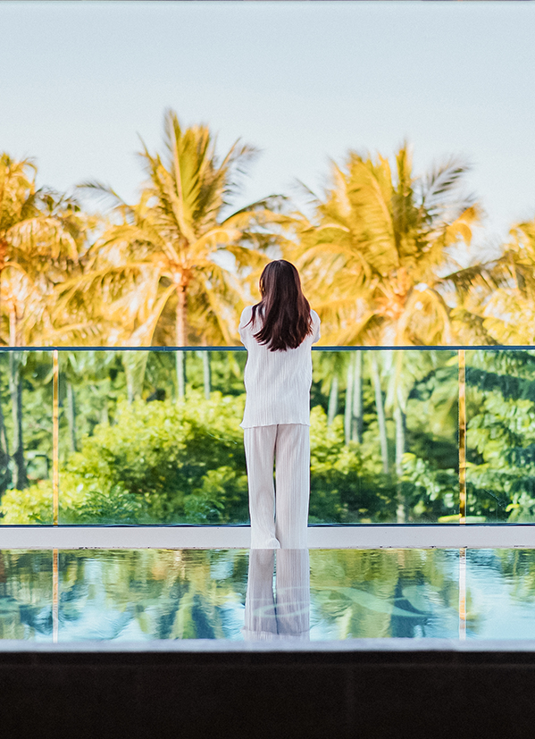 a woman standing on a pool with palm trees in the background