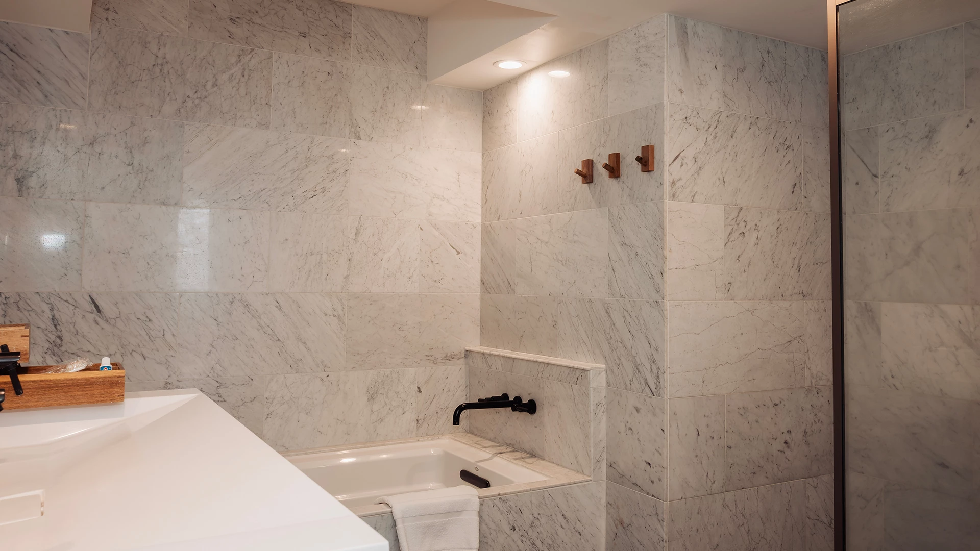 A bathroom with a marble tiled wall and a bathtub with a black faucet.