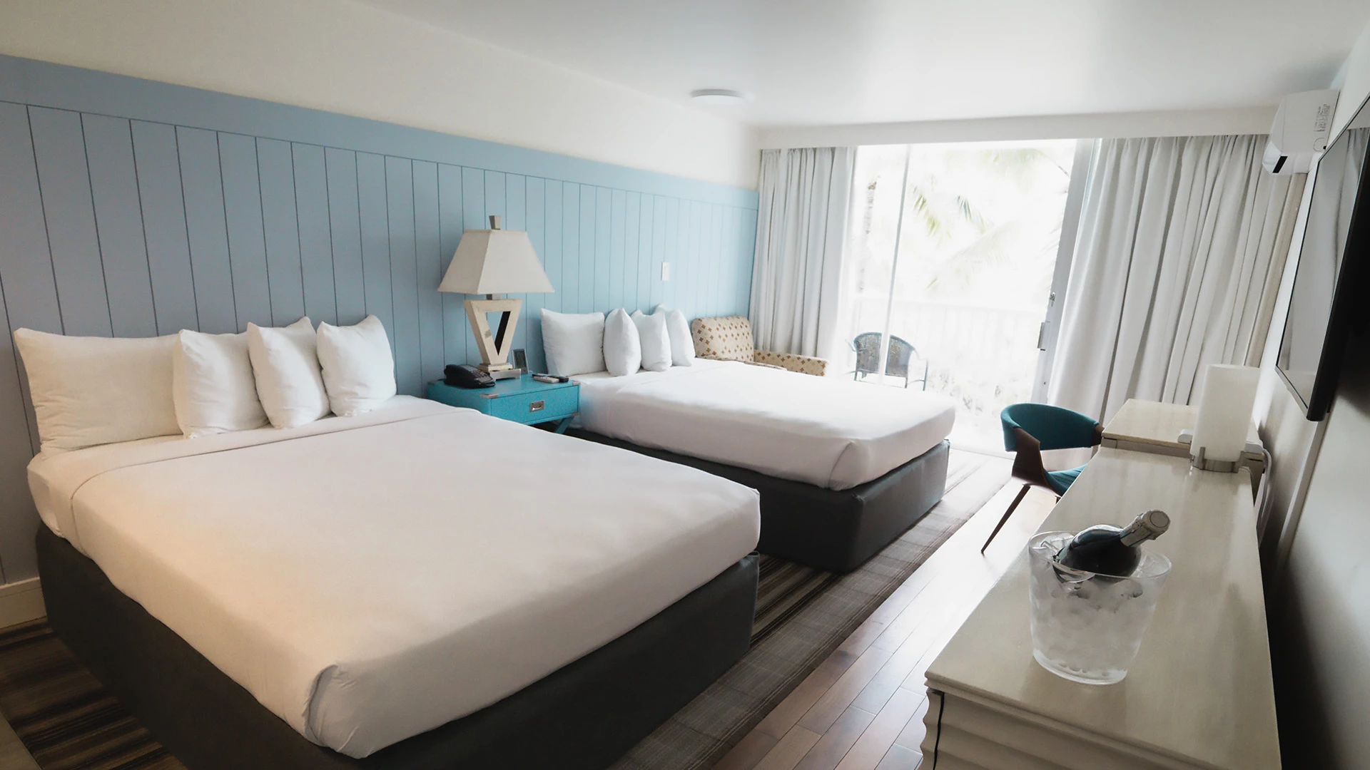 A hotel room with two twin beds, a desk, a window, and a TV.