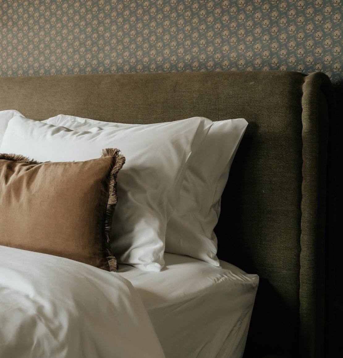 a bed with pillows and a brown pillow on it